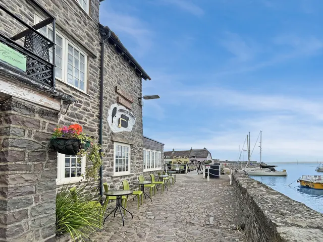 The stone terrace of the house, tables outside, the harbour beyond